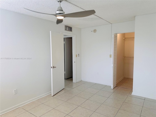 tiled empty room featuring ceiling fan and a textured ceiling