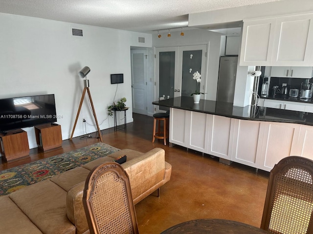 kitchen with white cabinets, french doors, a textured ceiling, and stainless steel refrigerator