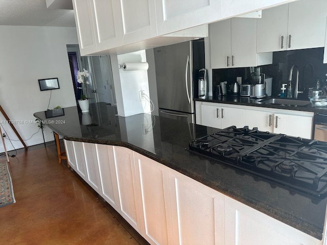 kitchen featuring black gas cooktop, stainless steel fridge, sink, and white cabinets