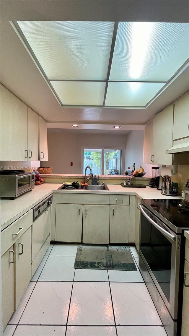 kitchen featuring dishwasher, cream cabinetry, stainless steel electric stove, and sink