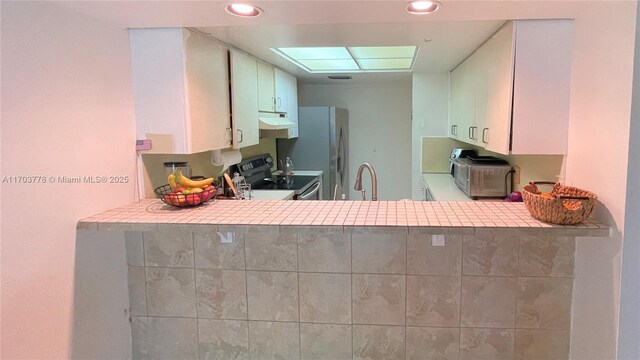 kitchen with kitchen peninsula, sink, white cabinets, and appliances with stainless steel finishes