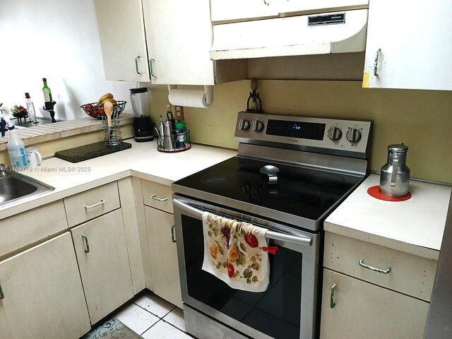 kitchen with stainless steel range with electric stovetop, ventilation hood, and light tile patterned floors