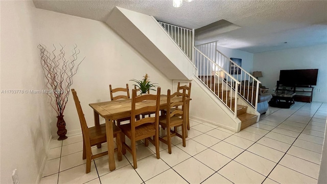 tiled dining space featuring a textured ceiling