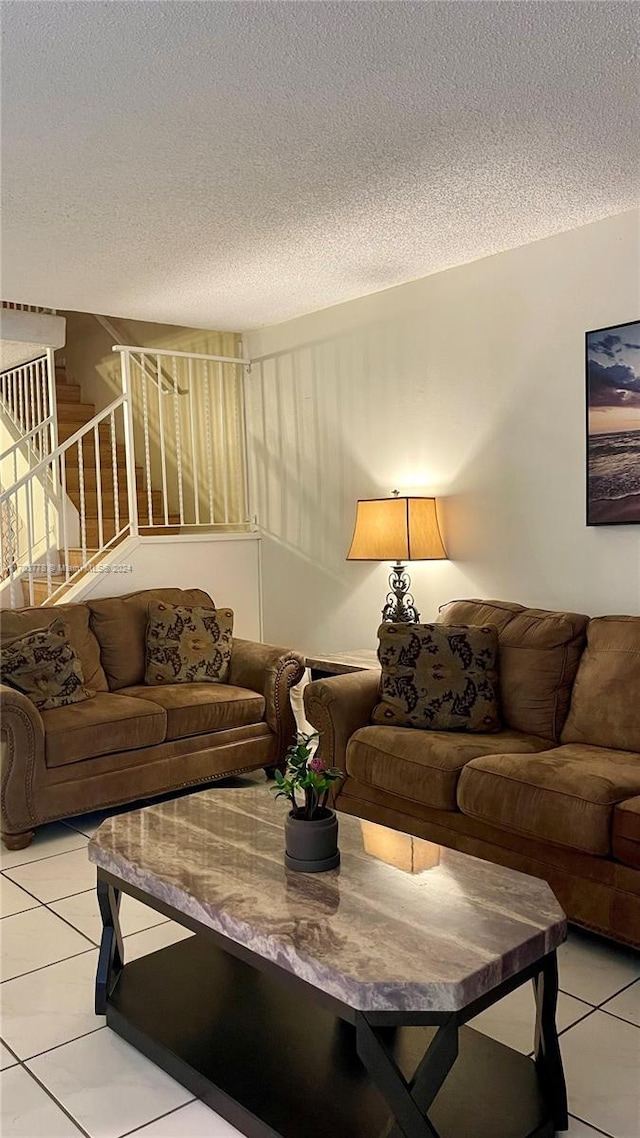 tiled living room featuring a textured ceiling