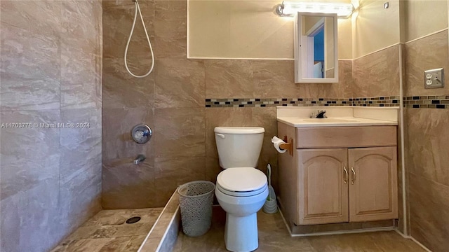 bathroom with toilet, vanity, tile walls, and walk in shower