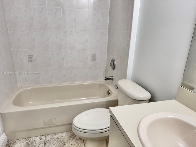 full bathroom featuring vanity, tiled shower / bath, and toilet