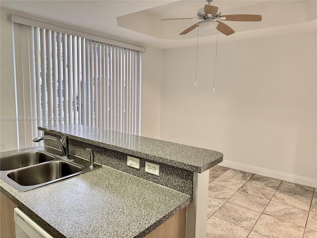 kitchen featuring sink, dishwasher, ceiling fan, light tile patterned flooring, and a raised ceiling