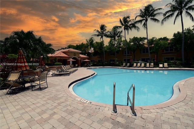 pool at dusk featuring a patio