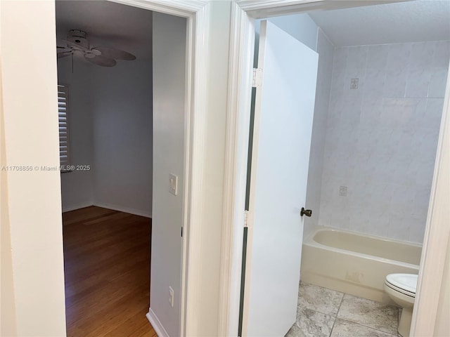 bathroom with a bathing tub, hardwood / wood-style floors, ceiling fan, and toilet