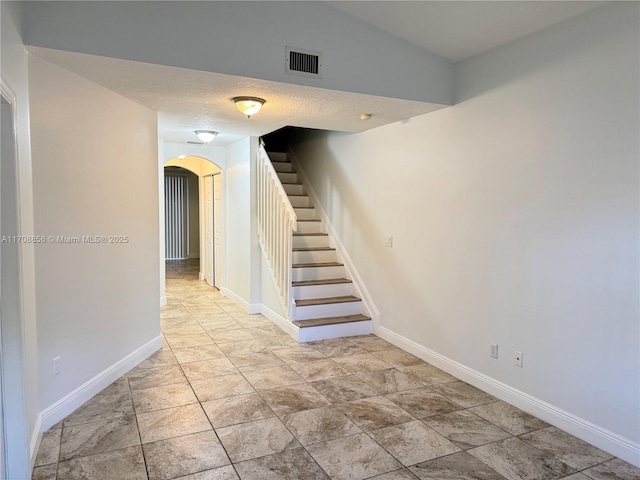 staircase featuring vaulted ceiling and a textured ceiling