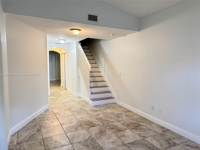 staircase with vaulted ceiling and a textured ceiling