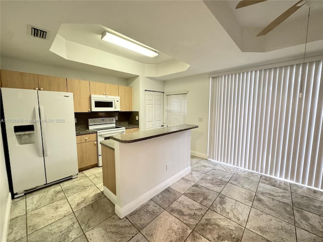 kitchen with tasteful backsplash, a center island, ceiling fan, a tray ceiling, and white appliances