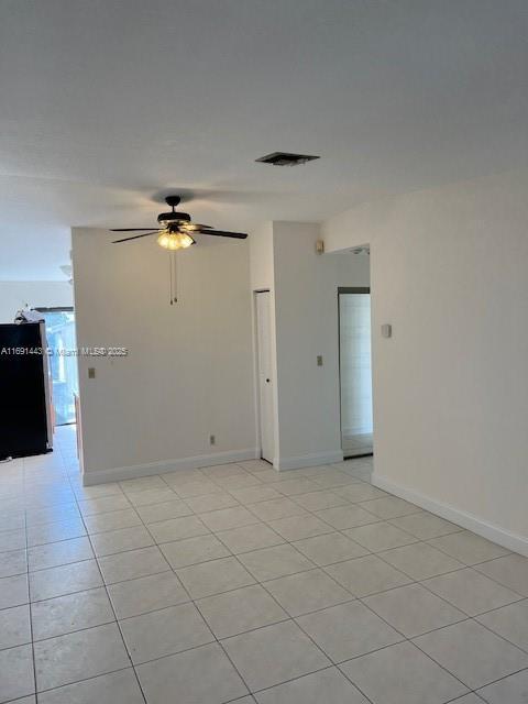 tiled spare room with ceiling fan