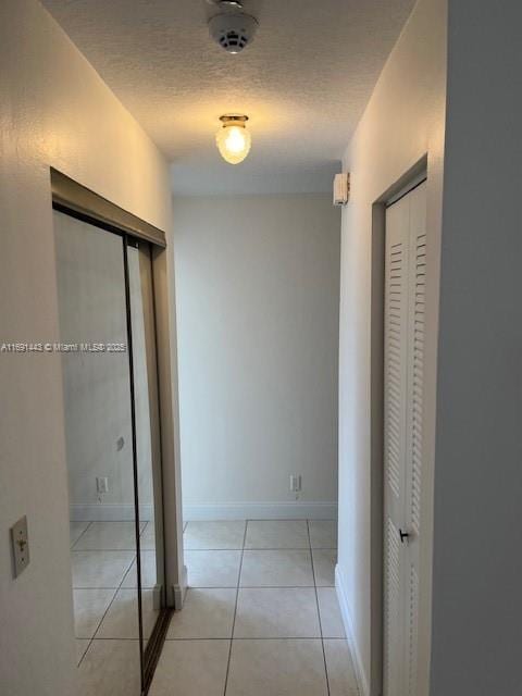 corridor featuring light tile patterned floors and a textured ceiling