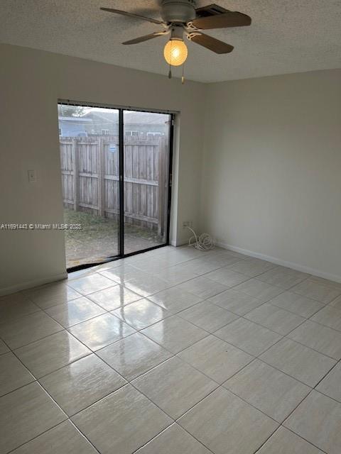 empty room featuring ceiling fan, light tile patterned floors, and a textured ceiling