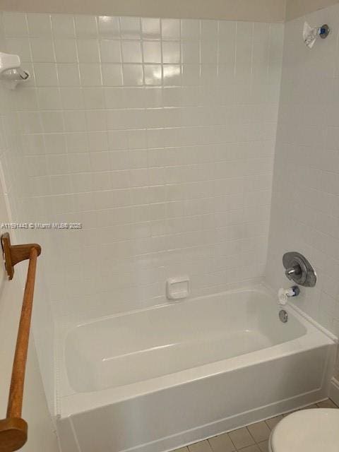 bathroom with toilet, tiled shower / bath combo, and tile patterned floors