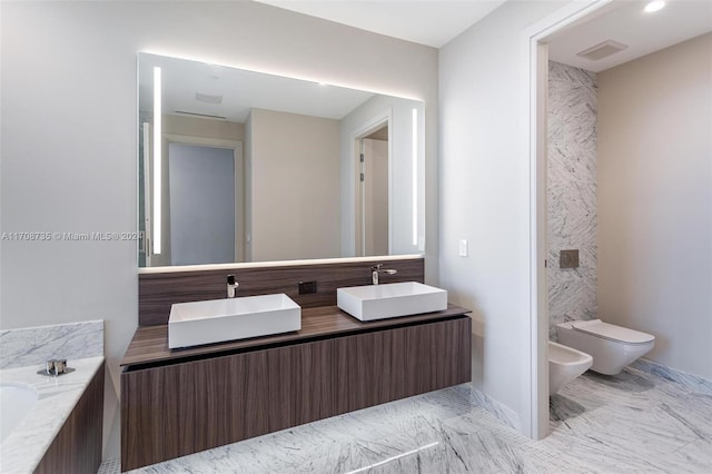 bathroom with vanity, toilet, a washtub, and a bidet