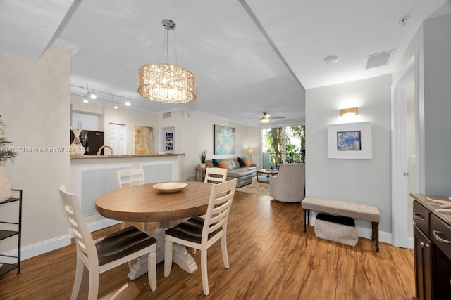 dining area with ornamental molding, ceiling fan with notable chandelier, and light wood-type flooring