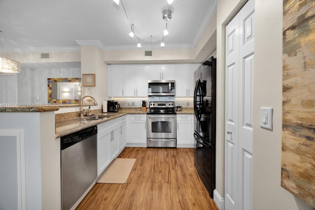 kitchen with light stone countertops, sink, kitchen peninsula, white cabinets, and appliances with stainless steel finishes