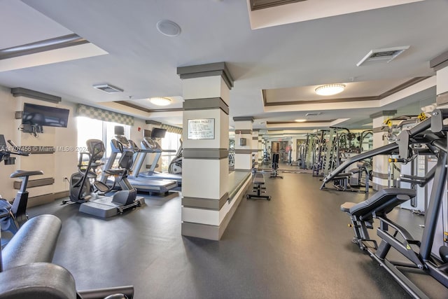 exercise room with crown molding and a tray ceiling