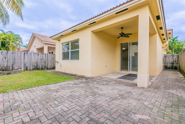 rear view of house featuring ceiling fan, a yard, and a patio