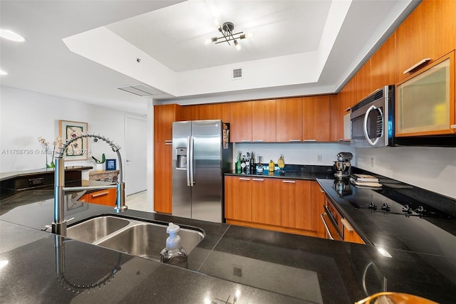 kitchen featuring stainless steel appliances, a raised ceiling, and sink