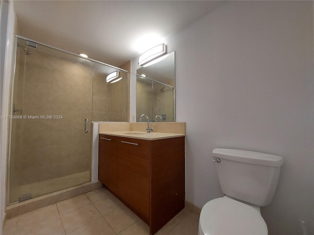 bathroom with toilet, vanity, tile patterned floors, and a shower with door