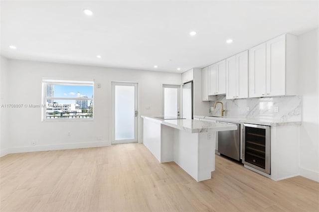 kitchen with wine cooler, white cabinets, stainless steel dishwasher, and light wood-type flooring