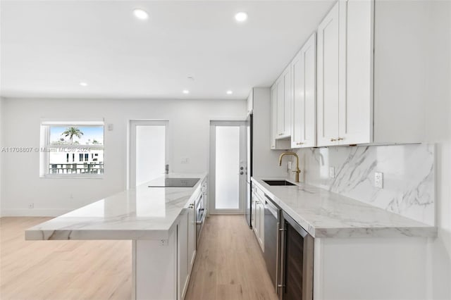 kitchen featuring light stone countertops, black electric stovetop, sink, light hardwood / wood-style flooring, and white cabinetry