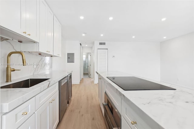 kitchen with light stone countertops, sink, stainless steel appliances, and light wood-type flooring