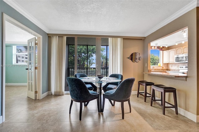 dining space featuring plenty of natural light, a textured ceiling, and ornamental molding