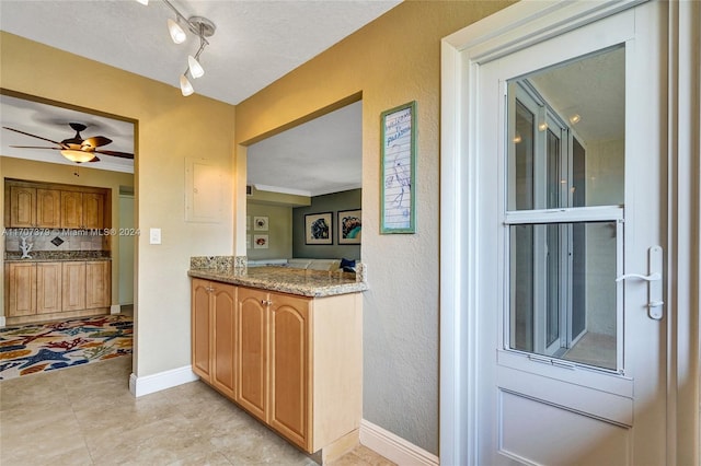 kitchen with backsplash, light stone counters, a textured ceiling, ceiling fan, and light tile patterned floors