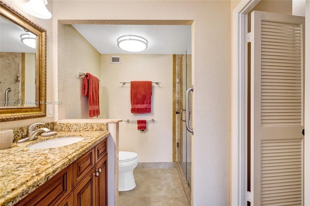 bathroom with tile patterned floors, vanity, a shower with shower door, and toilet