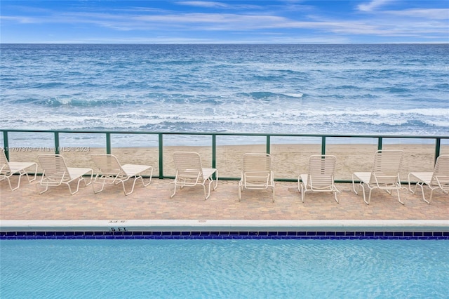 view of swimming pool featuring a water view and a view of the beach