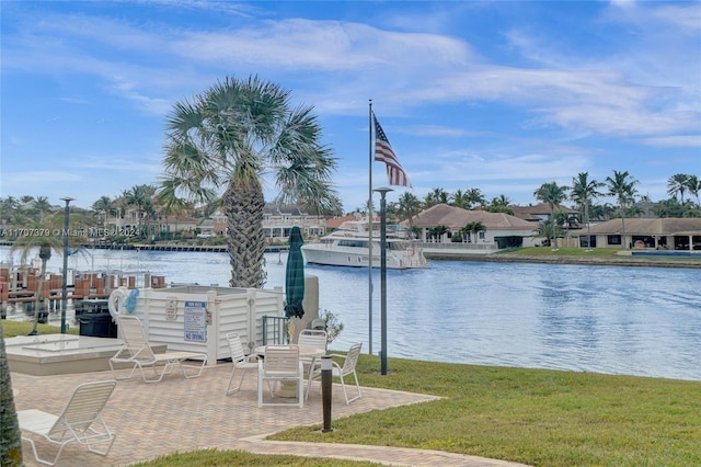 view of dock featuring a lawn, a water view, and a patio