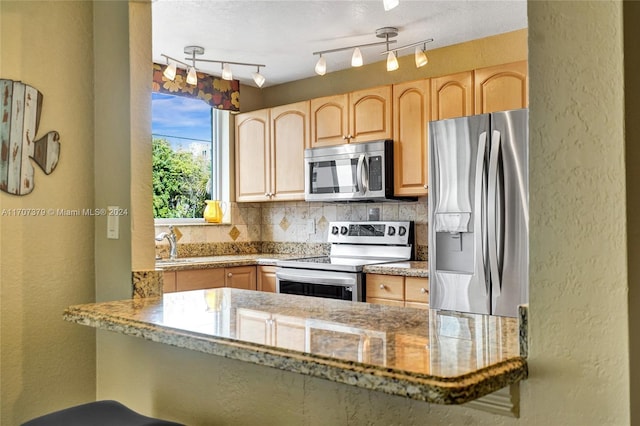 kitchen with kitchen peninsula, stainless steel appliances, light stone counters, and tasteful backsplash