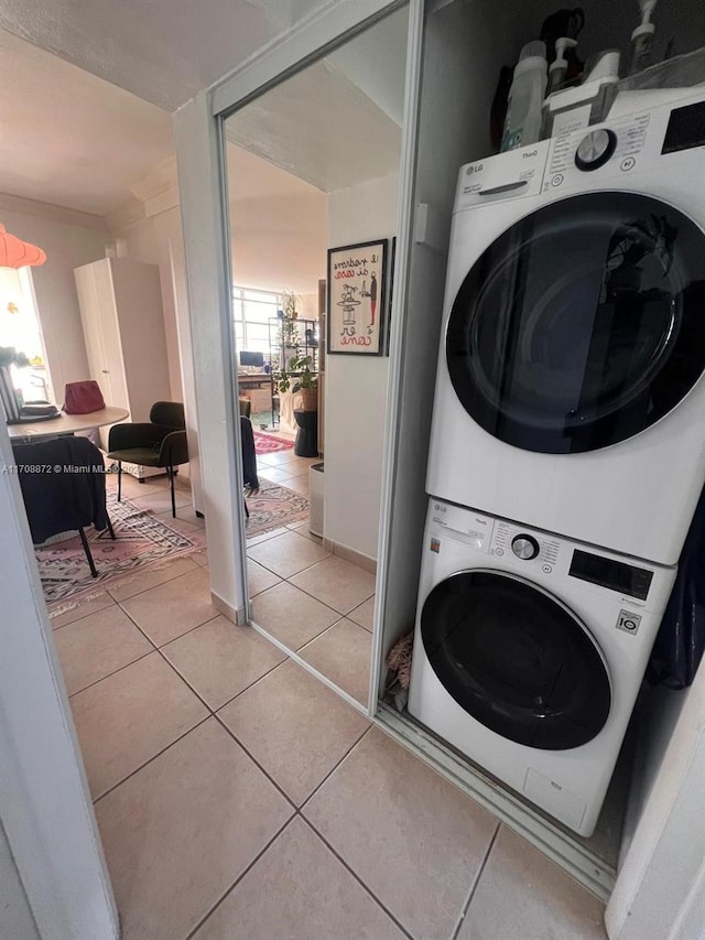 clothes washing area with light tile patterned flooring and stacked washer and clothes dryer