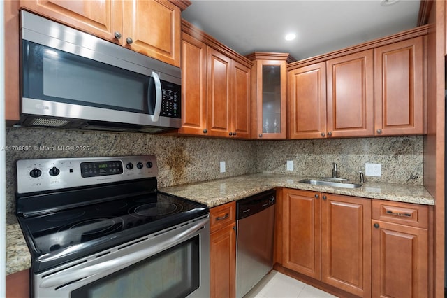 3675 N Country Club Dr Unit 105, Aventura, FL 33180 - kitchen with stainless steel appliances, backsplash, a sink, light stone counters, and glass insert cabinets