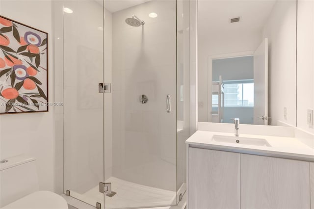 full bath featuring toilet, vanity, visible vents, and a stall shower