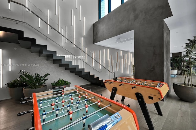 game room with a towering ceiling and hardwood / wood-style flooring