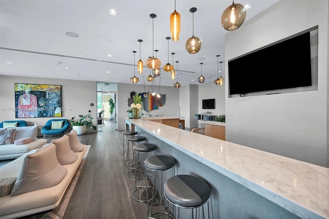 bar with pendant lighting, light stone countertops, and dark wood-type flooring