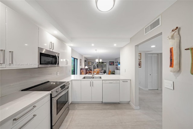 kitchen featuring white cabinets, sink, hanging light fixtures, kitchen peninsula, and stainless steel appliances