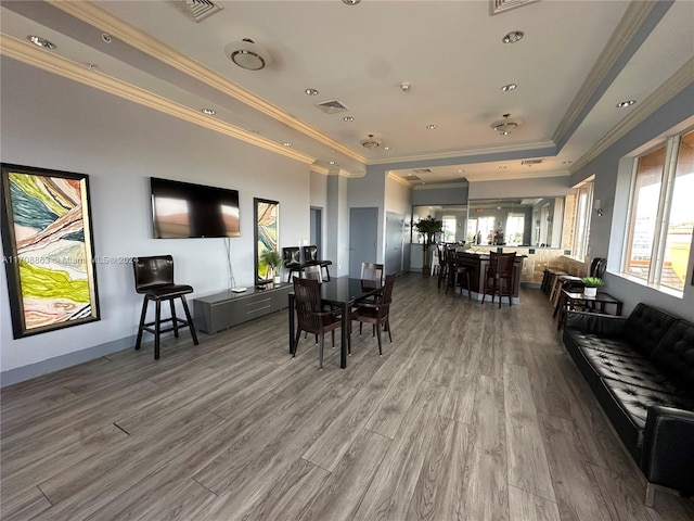 dining space featuring hardwood / wood-style flooring, a raised ceiling, and ornamental molding