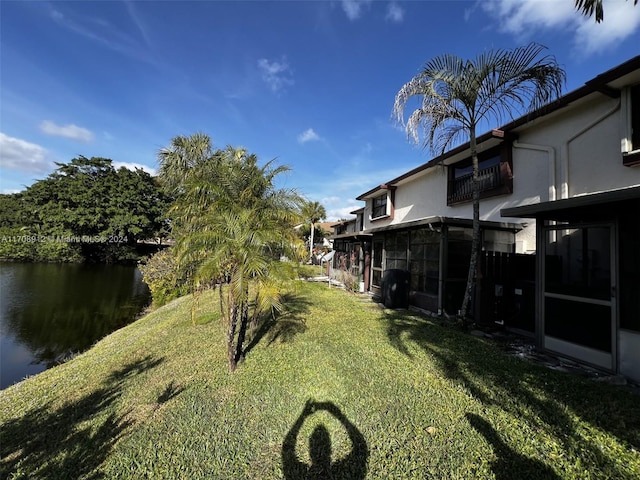 view of yard featuring a sunroom and a water view