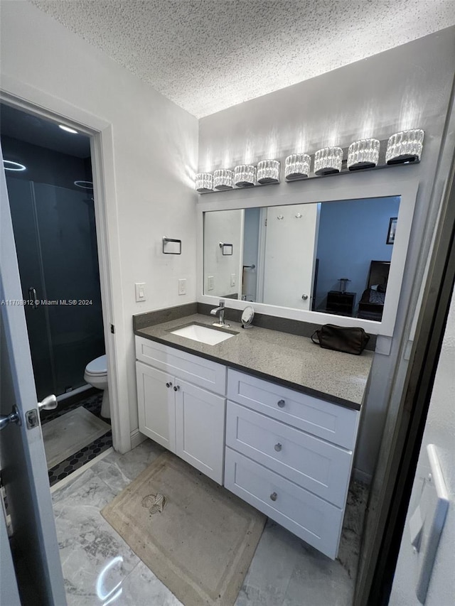 bathroom with vanity, toilet, a textured ceiling, and walk in shower