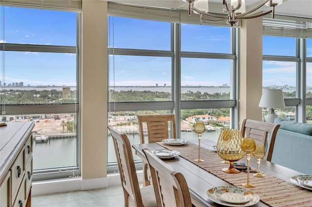 dining room featuring a chandelier, light tile patterned floors, and a water view