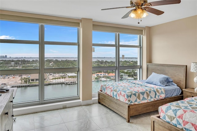 bedroom featuring ceiling fan, a water view, and light tile patterned floors