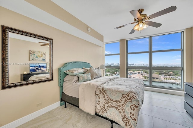 tiled bedroom with multiple windows, a wall of windows, a water view, and ceiling fan