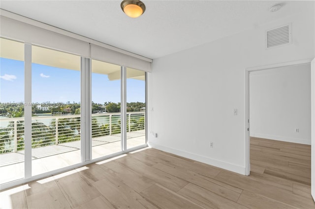 empty room with expansive windows and light wood-type flooring