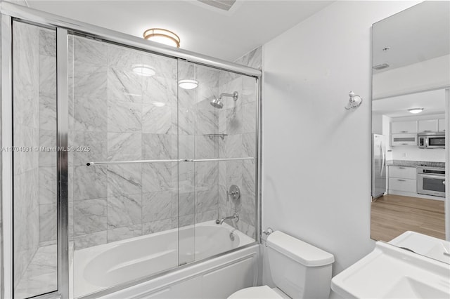 bathroom with toilet and combined bath / shower with glass door